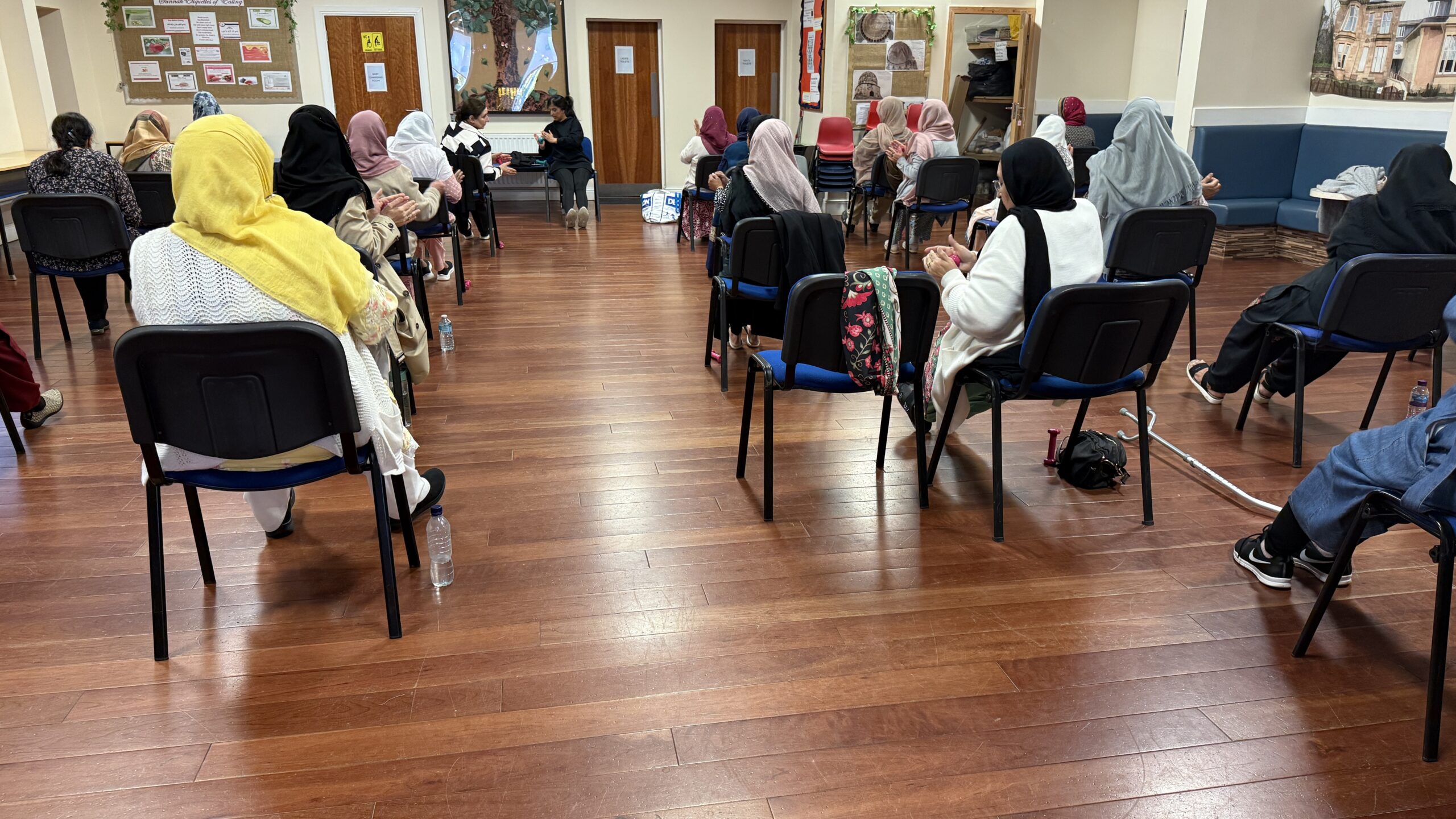 Photo from behind of a group of women doing seated exercise with hand weights
