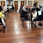 Photo from behind of a group of women doing seated exercise with hand weights