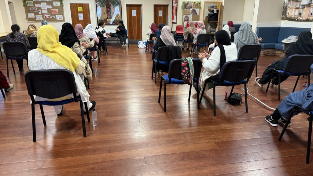 Photo from behind of a group of women doing seated exercise with hand weights